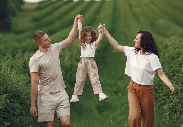 Joyful family moment in a green field during summer, capturing love and playfulness.